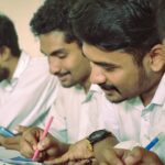 best laptop for coding and programming india - a group of men sitting at a table writing on paper