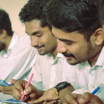 best laptop for coding and programming india - a group of men sitting at a table writing on paper