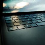 how to fix slow laptop - A laptop computer sitting on top of a wooden table