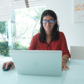 Woman smiles while working on a laptop.