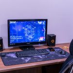 a desk with a computer and speakers on it