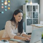 Woman working on laptop with man behind her