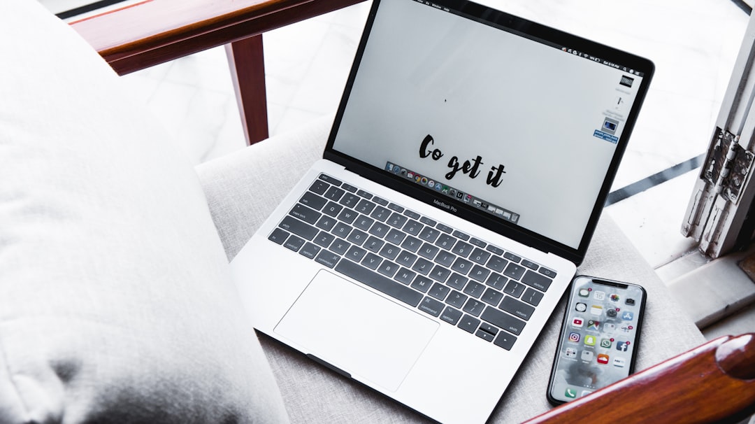 Laptop on a sofa shows the phrase 'Go get it' on screen, with a smartphone nearby on the armrest.