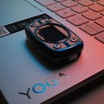 Pulse oximeter on a silver yoga laptop under colorful light.