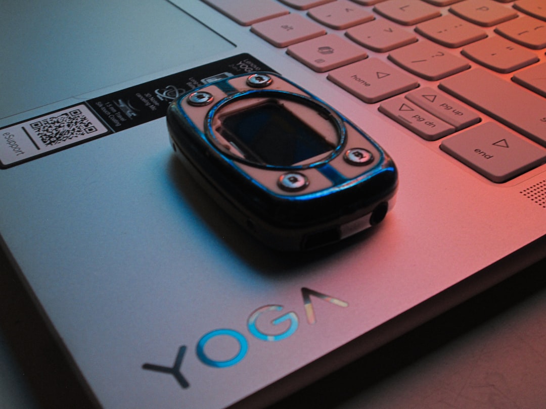 Pulse oximeter on a silver yoga laptop under colorful light.