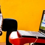 a man sitting in a chair with a laptop on his lap