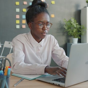 A woman working on a laptop in an office